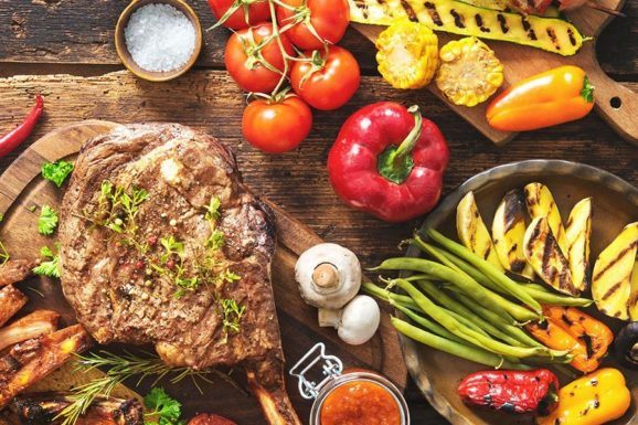 Grilled meat and vegetables on rustic wooden table - SoulSpice